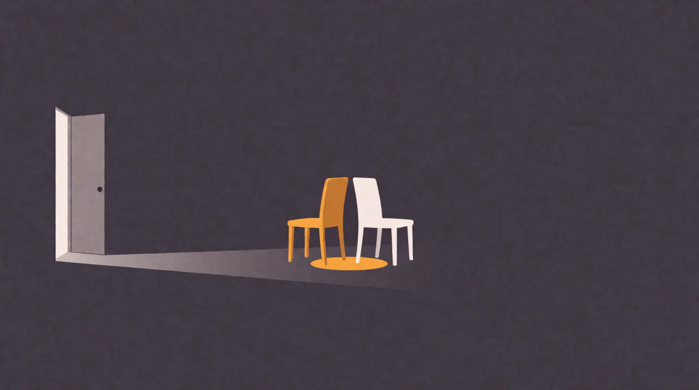 Two chairs, one amber and one off-white, facing each other on a small pool of warm light, an open door spilling pale light behind them